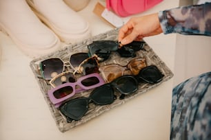 a person holding a pair of sunglasses on top of a tray