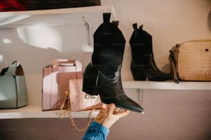 a woman holding up a pair of black boots