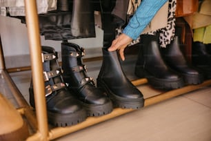 a close up of a person's hand touching a pair of black boots