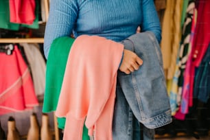 una donna che tiene un paio di jeans davanti a uno scaffale di vestiti