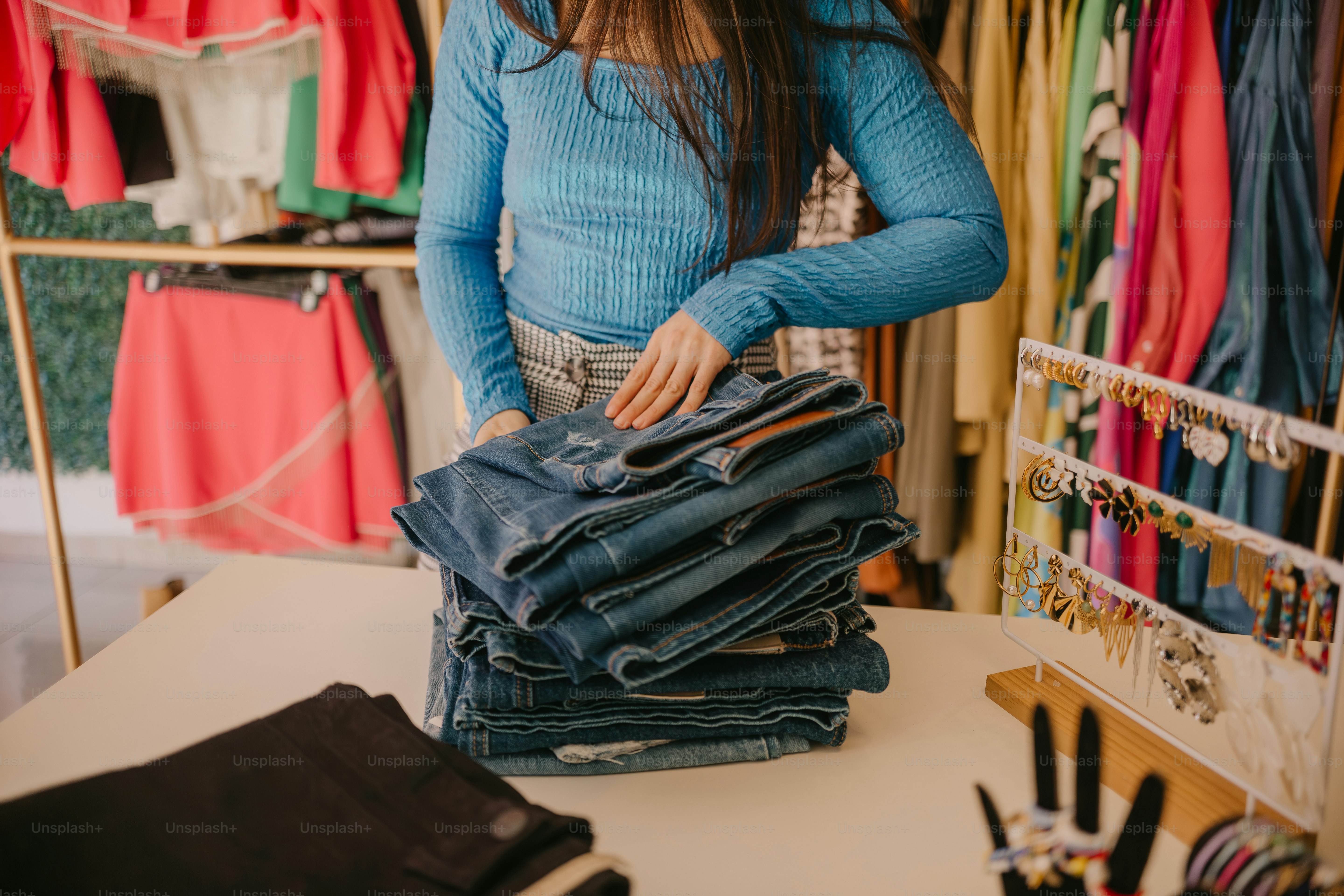 una donna in piedi davanti a una pila di jeans