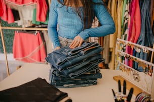 a woman standing in front of a pile of jeans