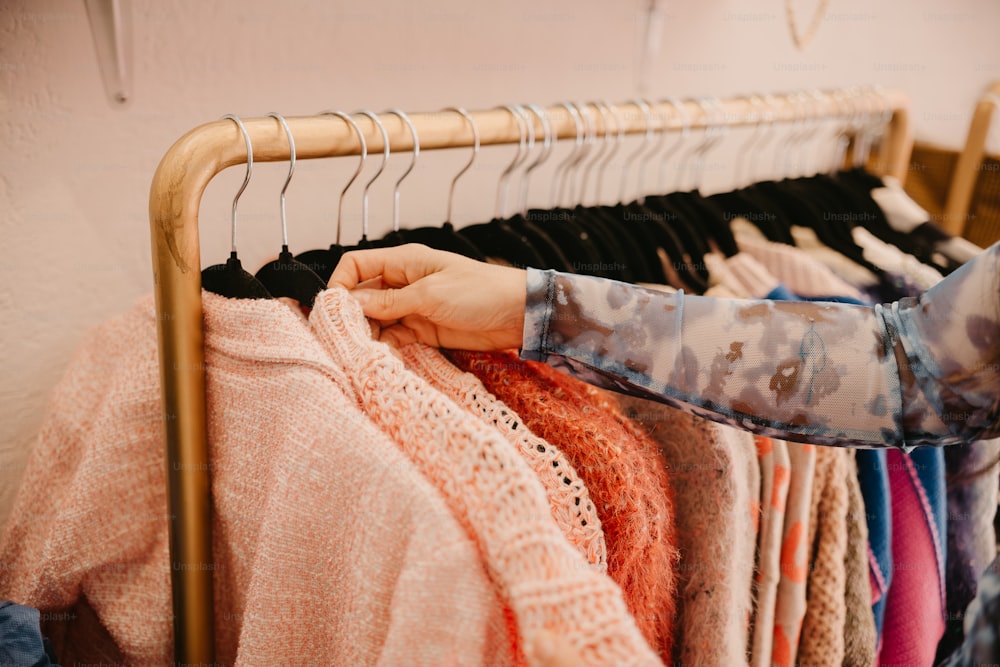 a woman is looking at a rack of sweaters