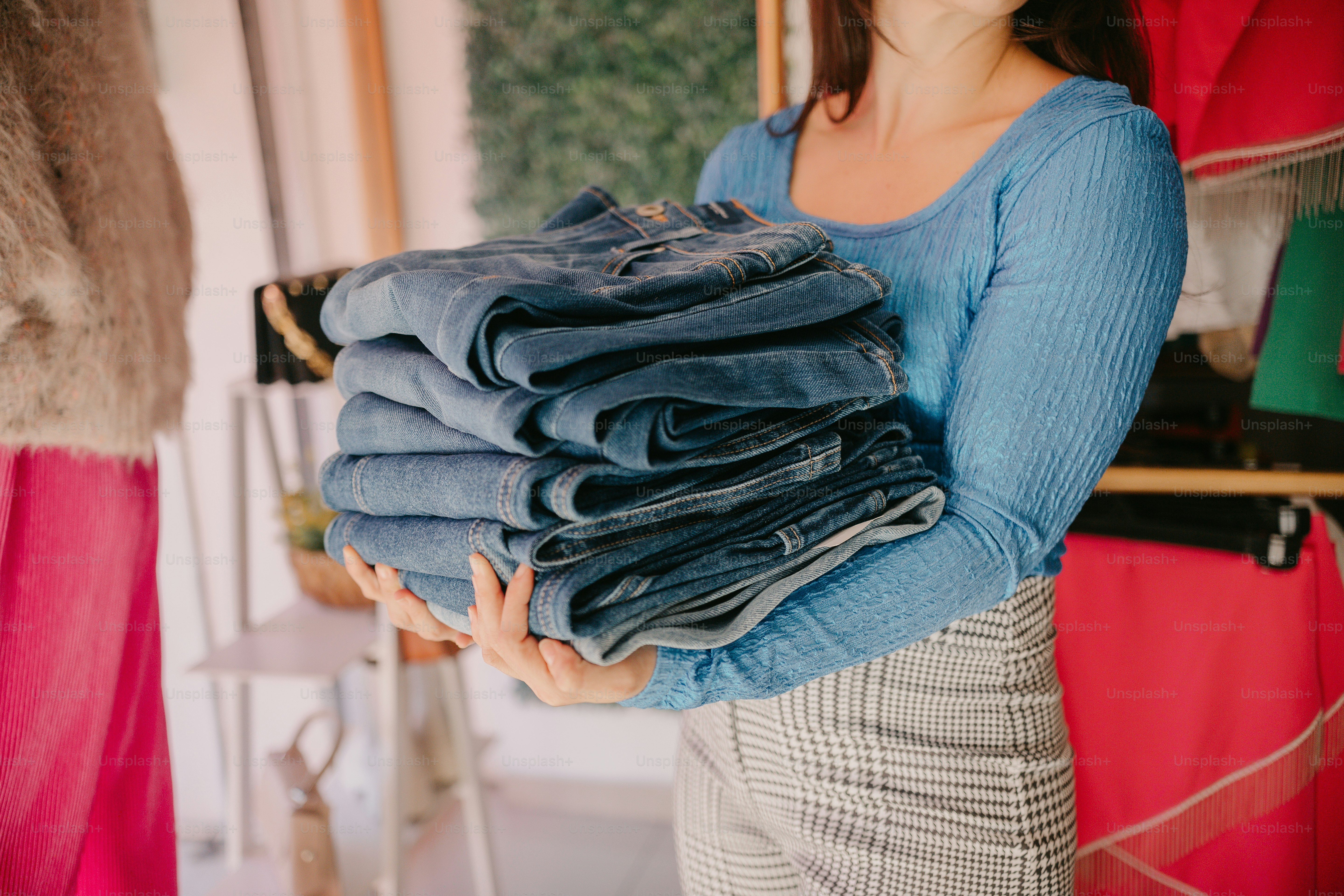 una donna che tiene una pila di jeans tra le mani