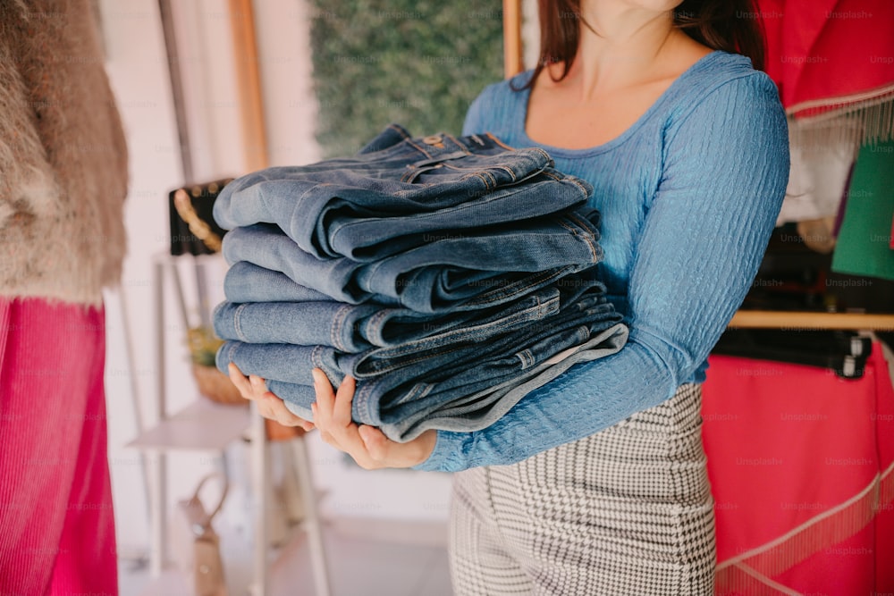 a woman holding a stack of jeans in her hands
