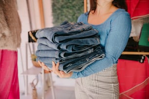 a woman holding a stack of jeans in her hands