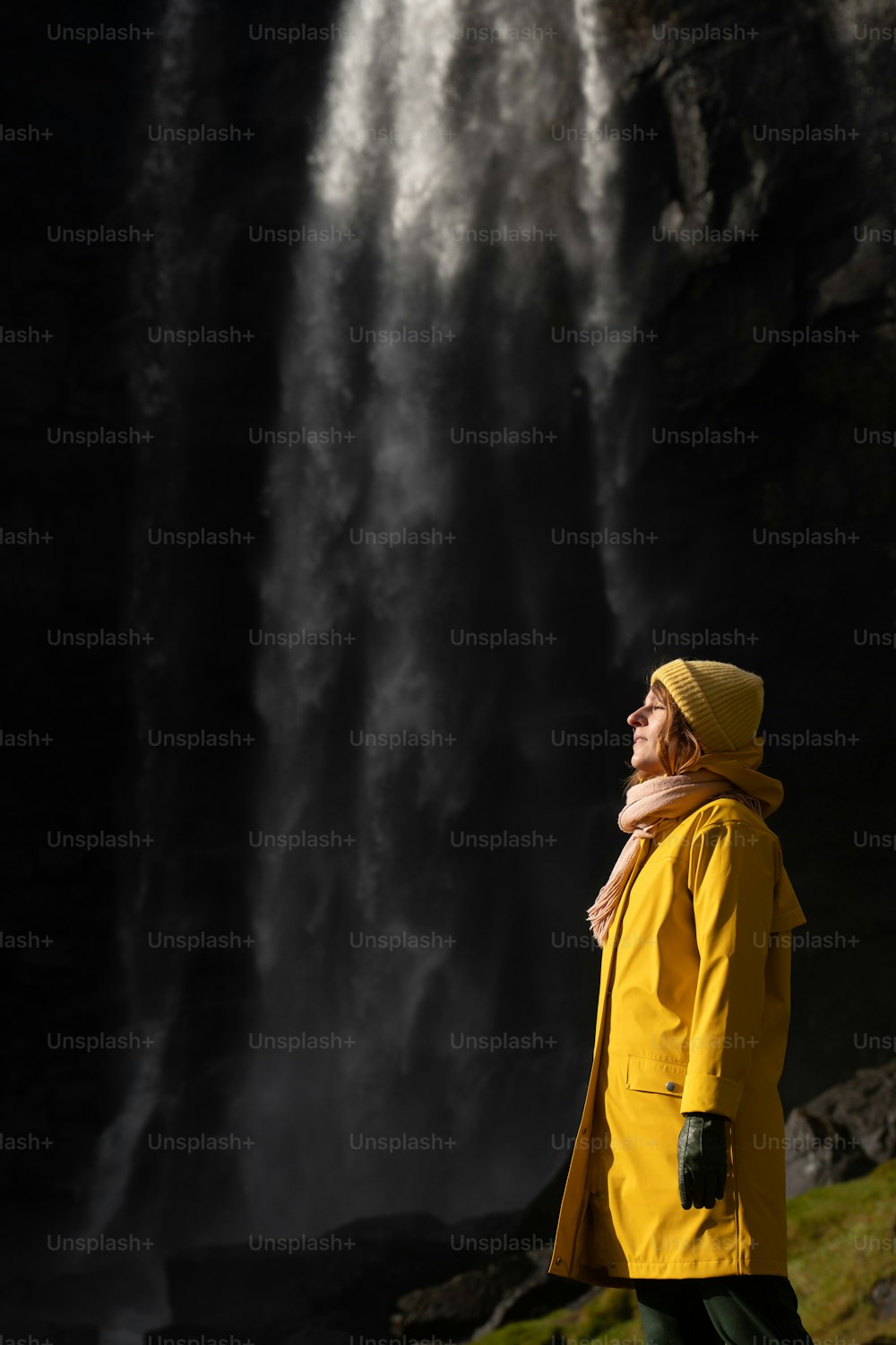 Un hombre con un impermeable amarillo parado frente a una cascada