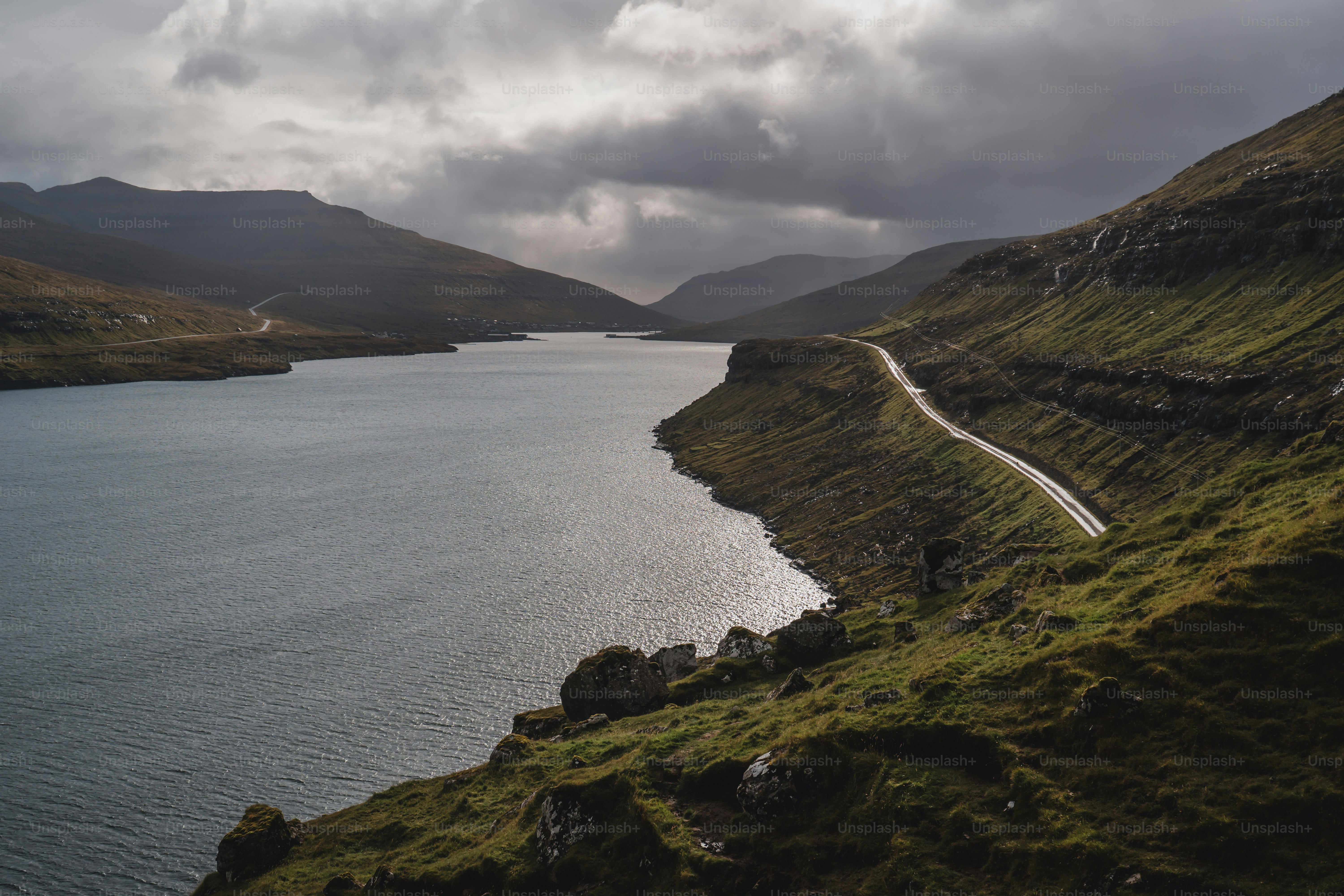 una strada che scende da una collina accanto a uno specchio d'acqua