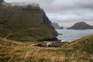 a group of people walking up a hill next to a body of water