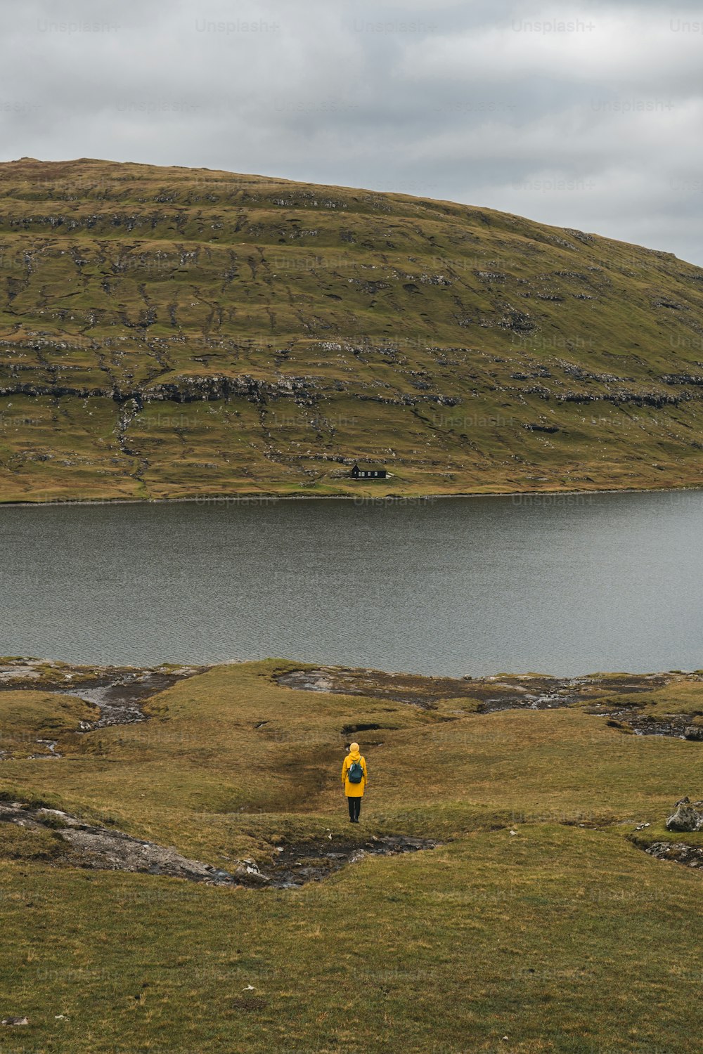 a person in a yellow jacket standing in front of a body of water