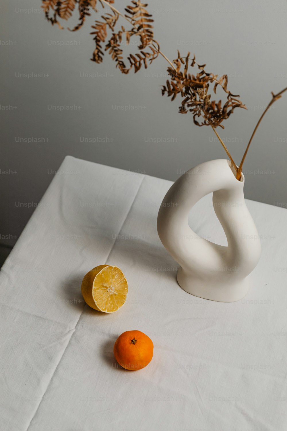 um vaso branco sentado em cima de uma mesa ao lado de uma laranja