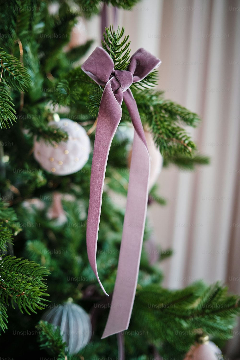 a close up of a christmas tree with a pink ribbon