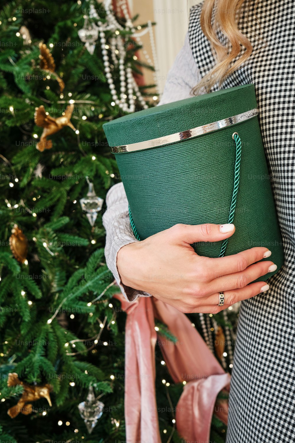 Una mujer sosteniendo una taza verde frente a un árbol de Navidad