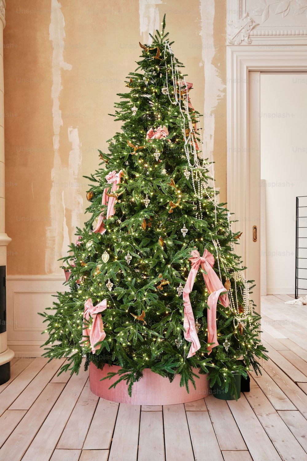 a decorated christmas tree with pink bows in a room