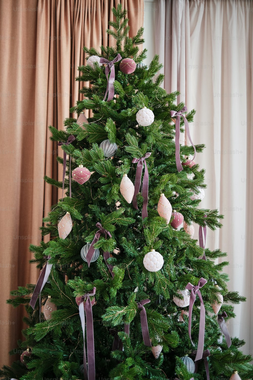 a decorated christmas tree with purple ribbons