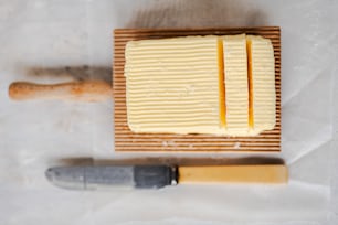 un bloque de mantequilla junto a un cuchillo en una tabla de cortar