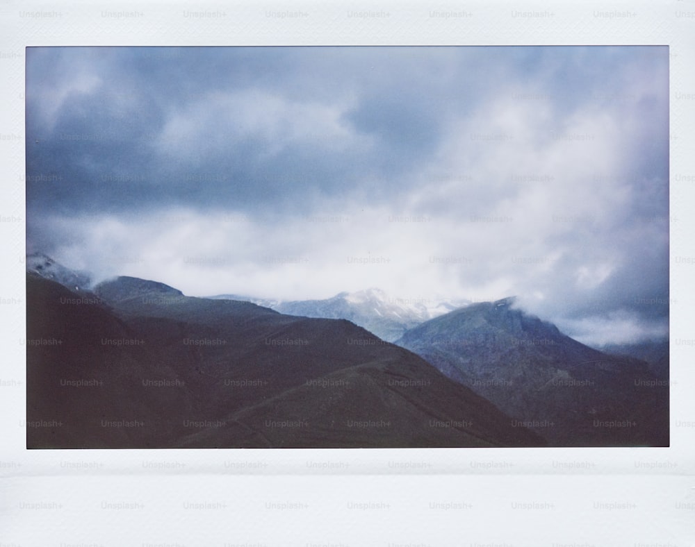 a picture of a mountain range under a cloudy sky