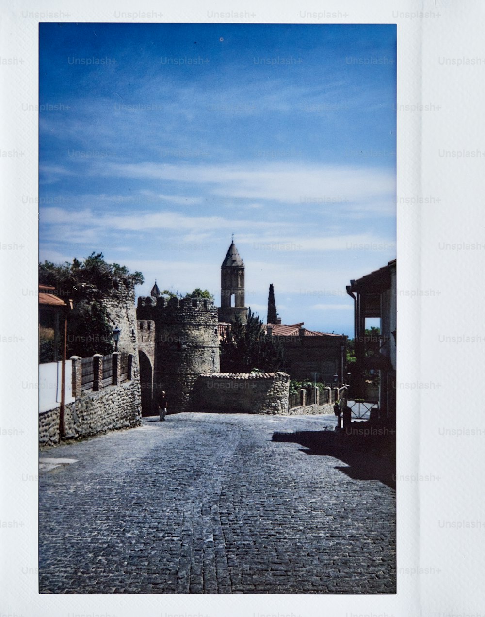 a picture of a cobblestone street with a clock tower in the background