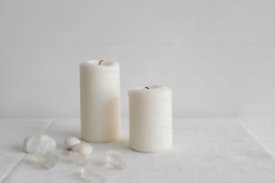 a couple of white candles sitting on top of a table