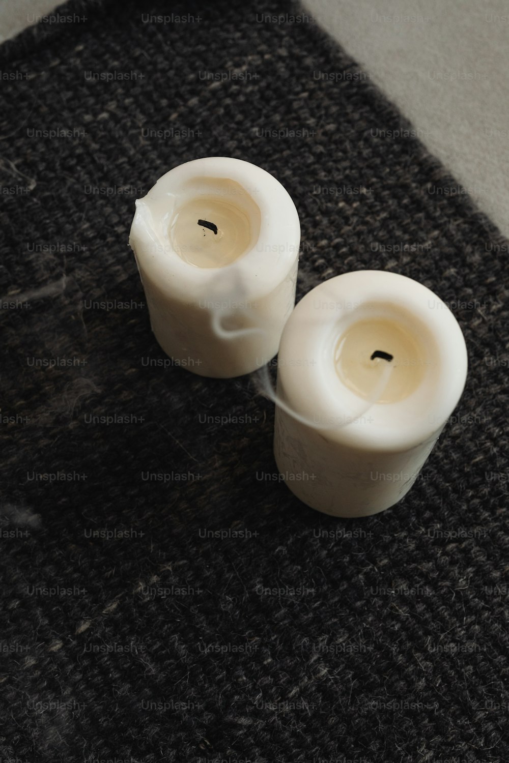 two white candles sitting on top of a table