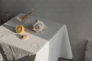 uma mesa com uma toalha de mesa branca e duas laranjas sobre ela