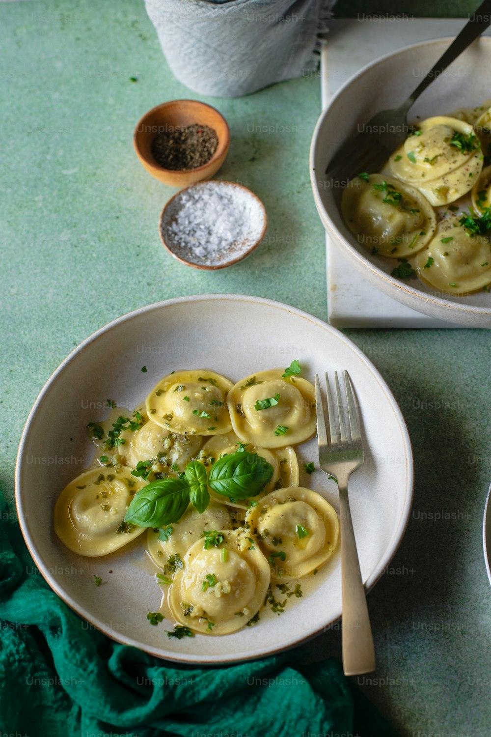 two plates of ravioli with pesto and parsley
