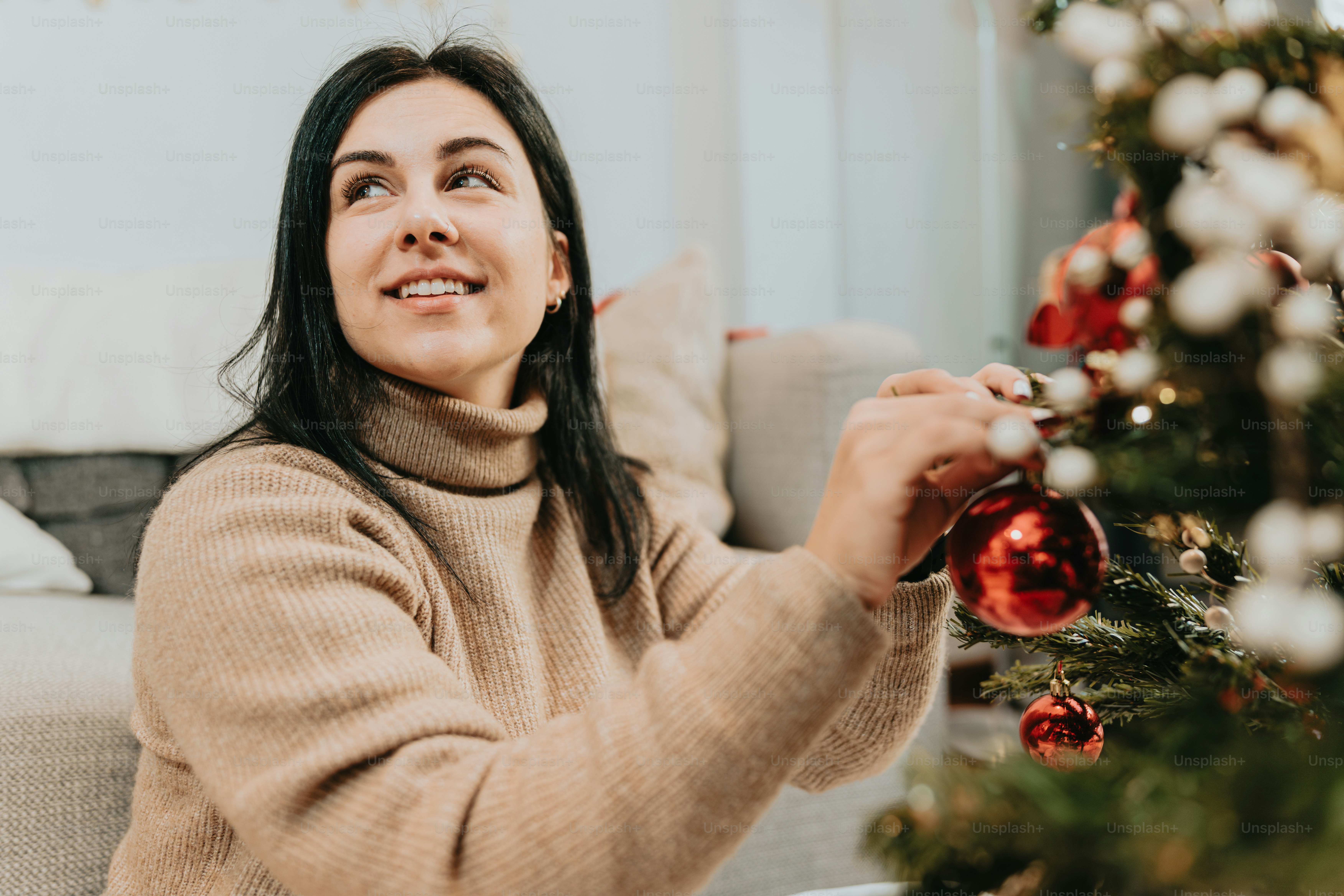 Une femme assise sur un canapé décorant un arbre de Noël photo – Image ...