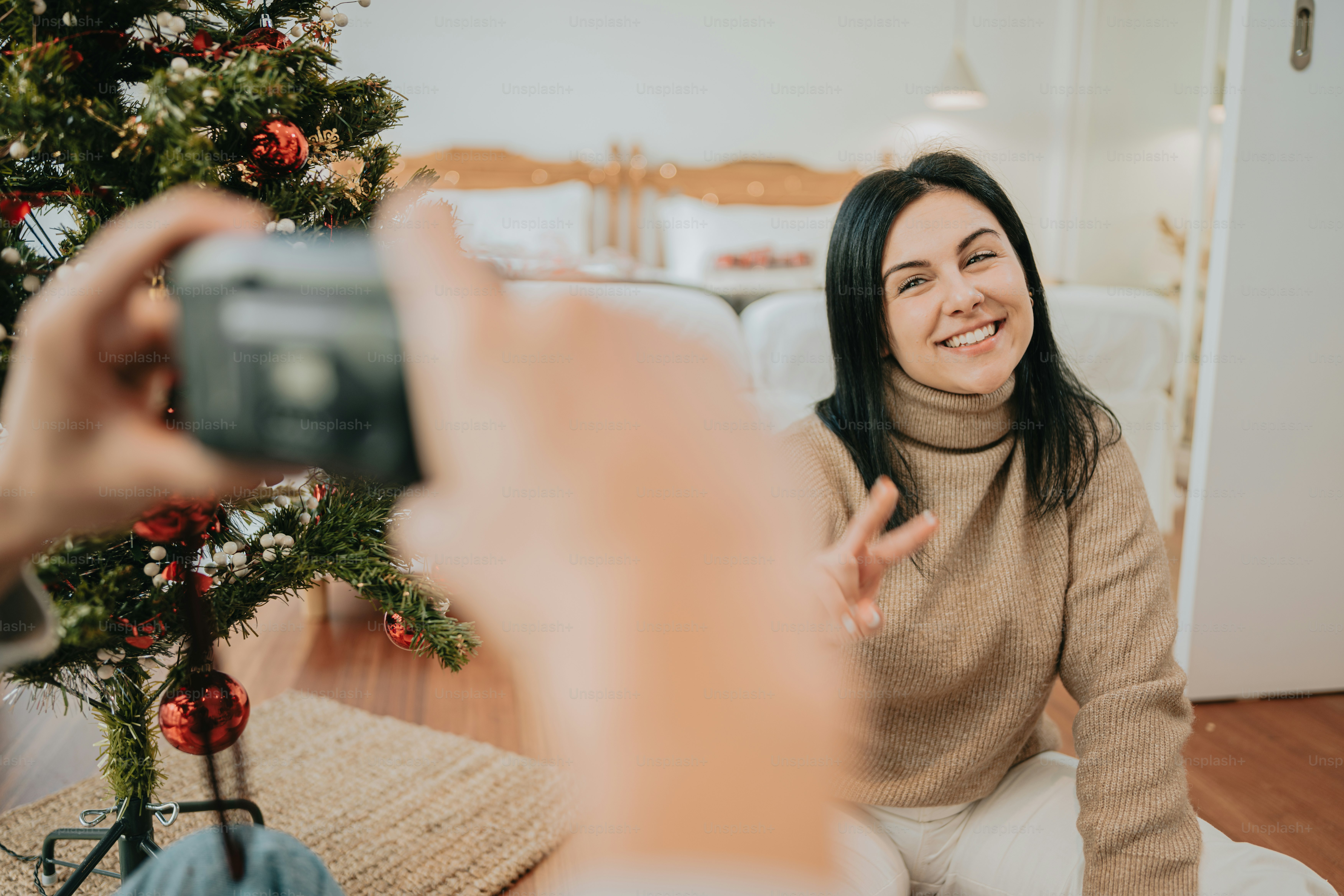 a woman taking a picture of a christmas tree