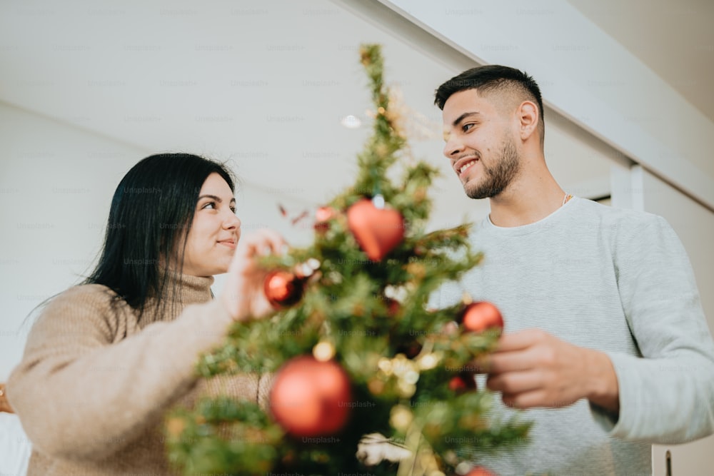 Um homem e uma mulher decorando uma árvore de Natal