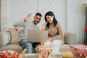 a man and woman sitting on a couch looking at a laptop