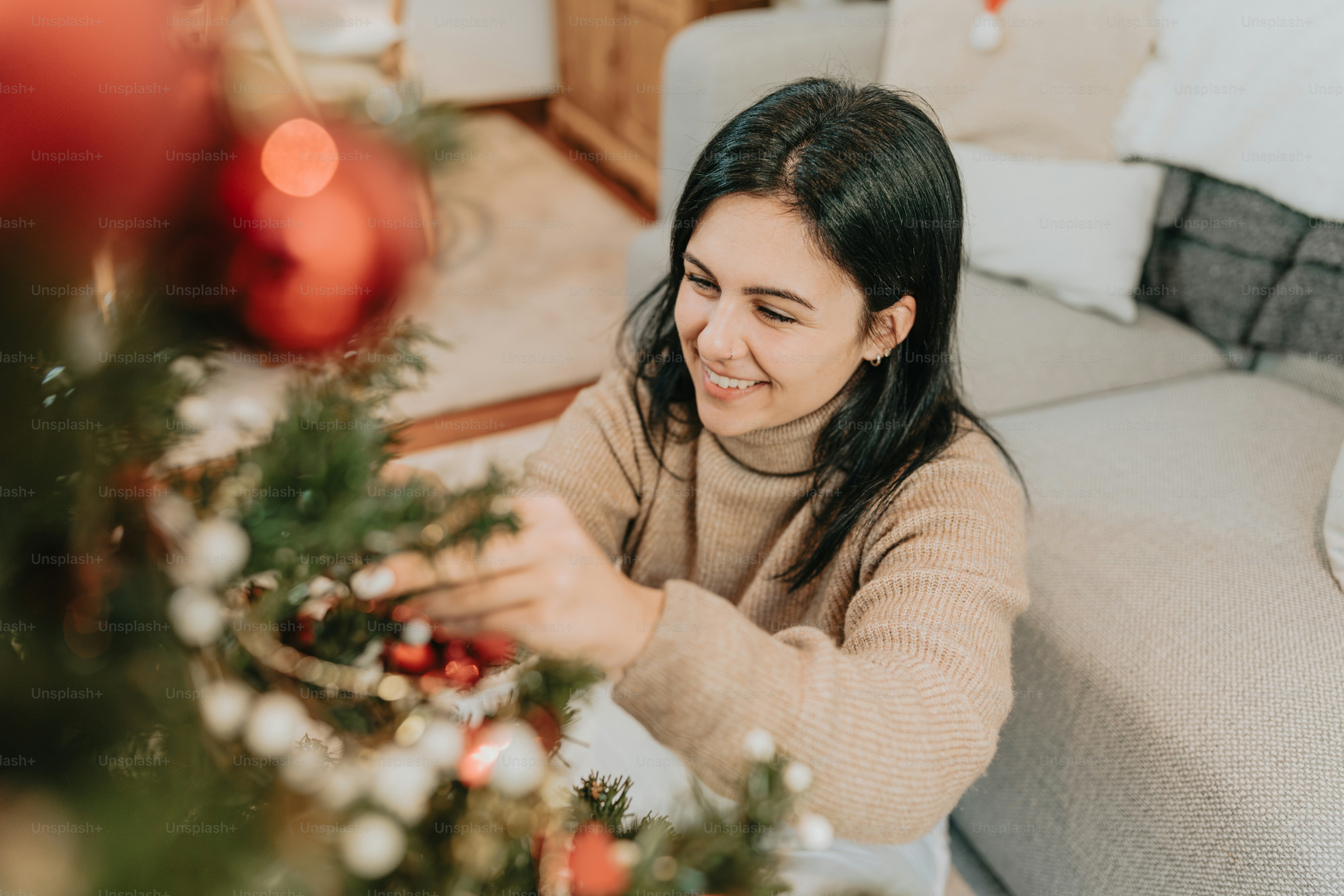 Une femme assise sur un canapé décorant un arbre de Noël photo – Image ...