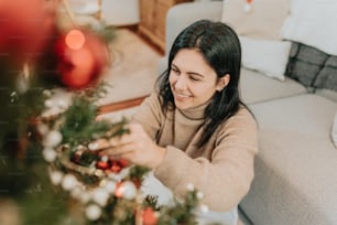 a woman sitting on a couch decorating a christmas tree