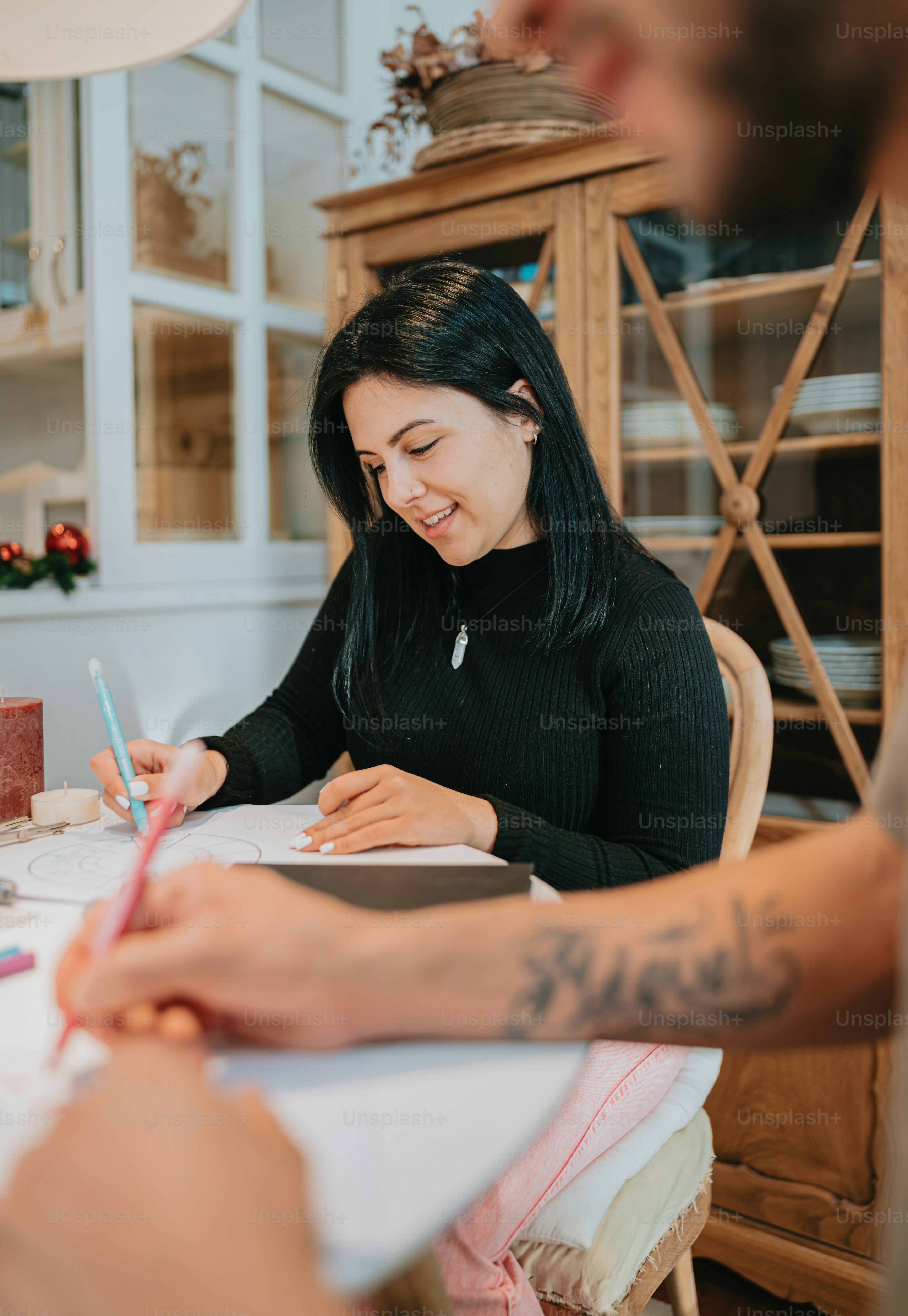 a woman sitting at a table writing on a piece of paper
