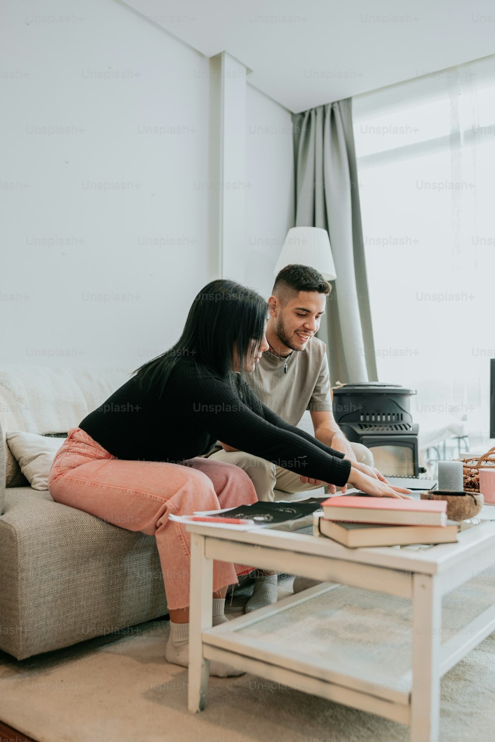 a man and woman sitting on a couch looking at a book