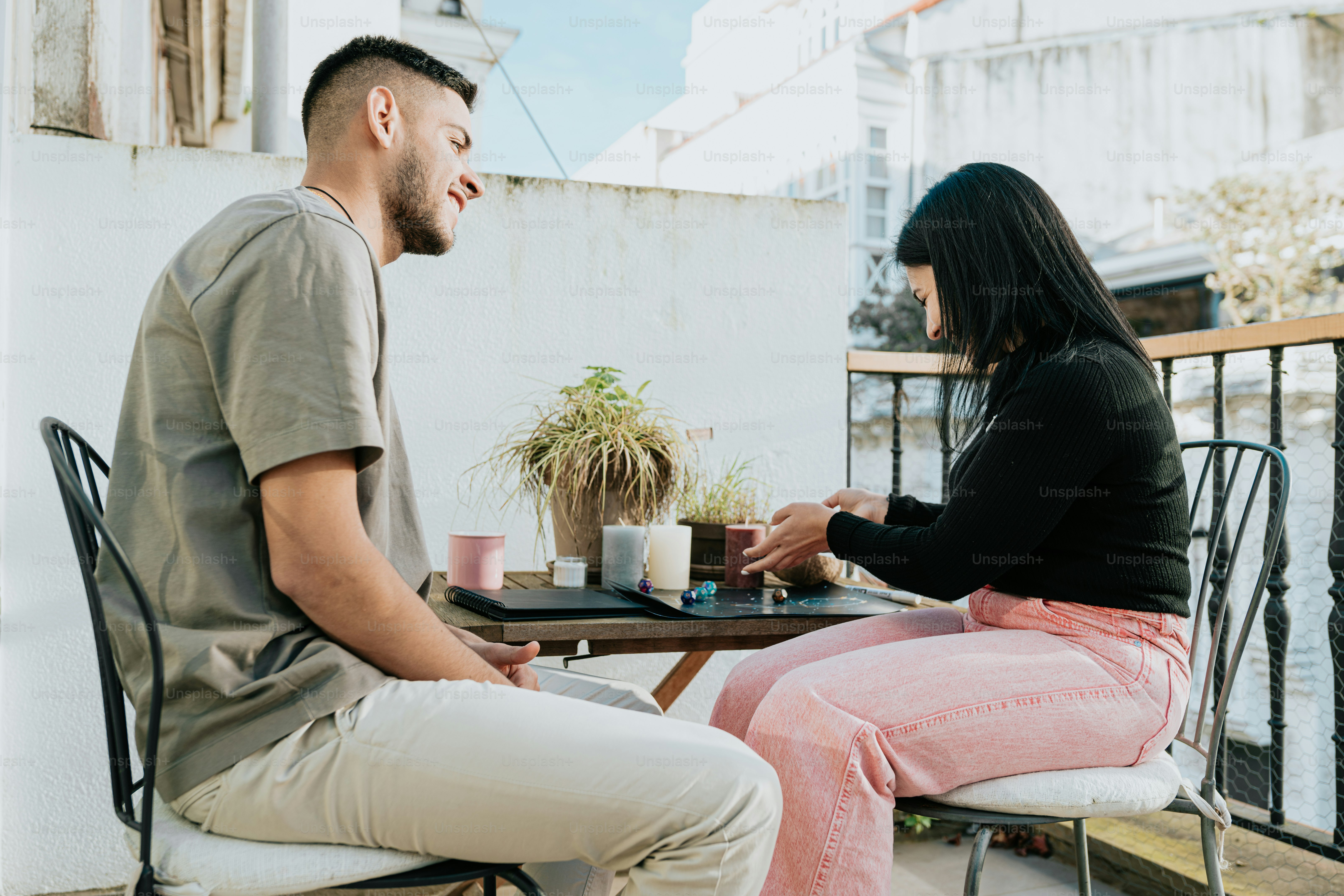 a man and a woman sitting at a table on a balcony