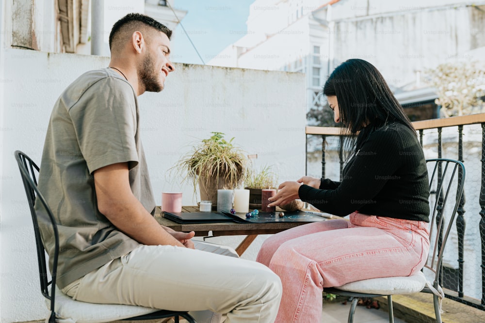 un homme et une femme assis à une table sur un balcon