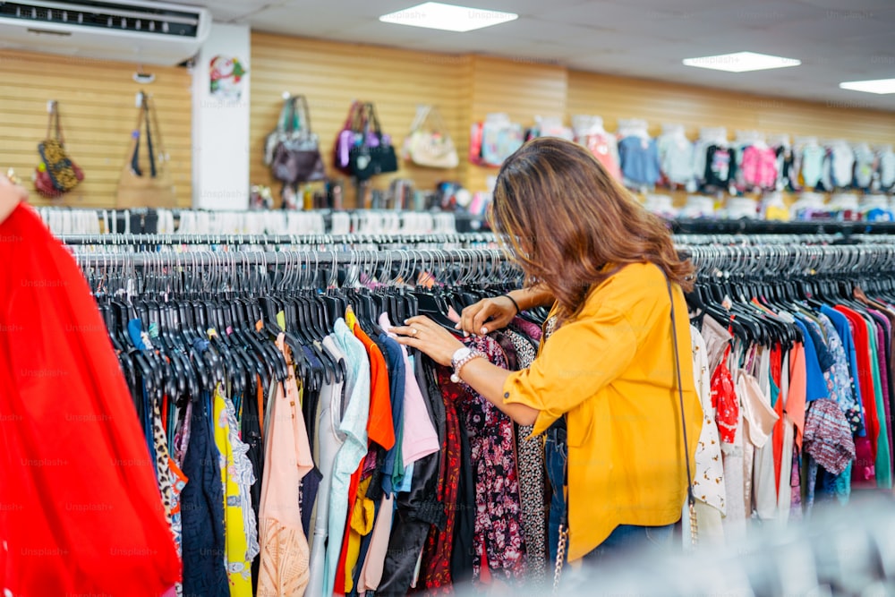 a woman looking at a rack of clothes