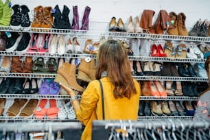 a woman looking at a rack of shoes