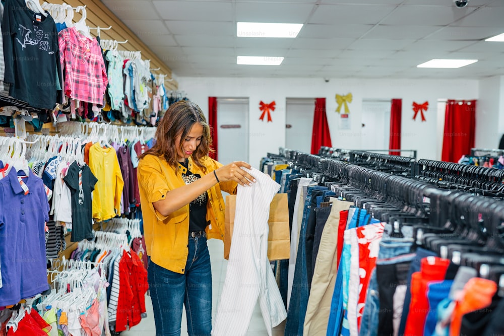 a woman in a yellow shirt is looking at clothes