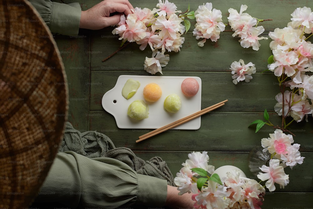 a person sitting at a table with a plate of food and flowers