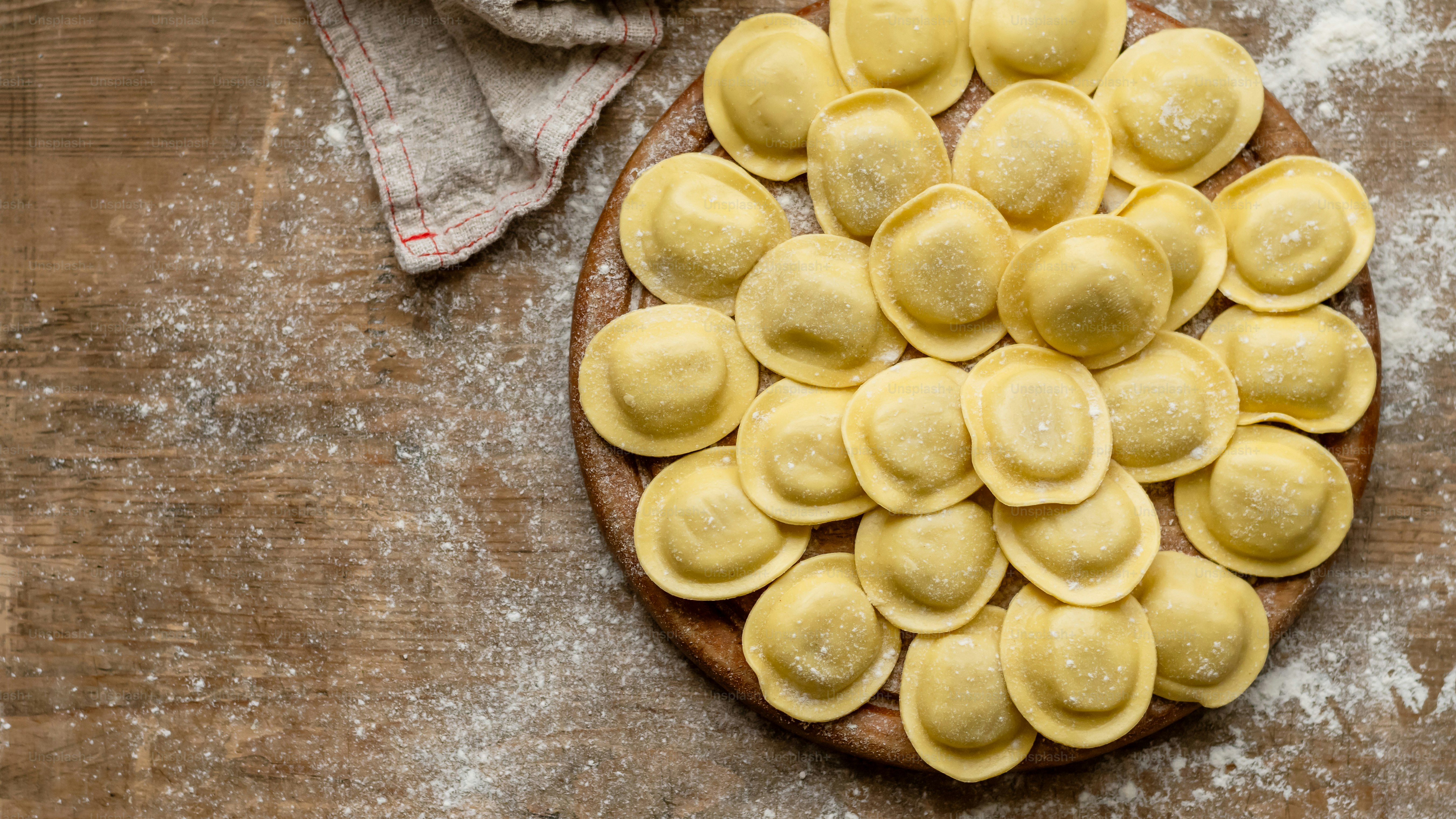 ein Holztisch mit einem Teller Ravioli