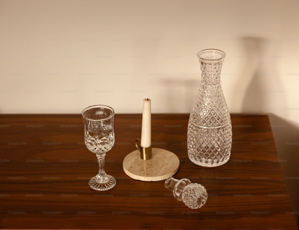 a wooden table topped with a vase and two glasses