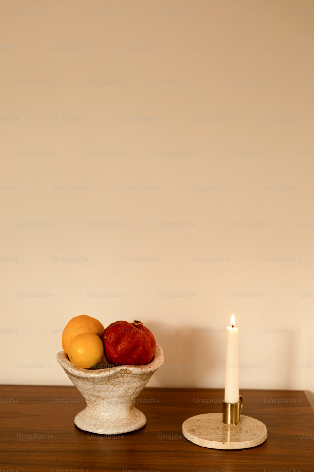 a bowl of fruit on a table next to a candle