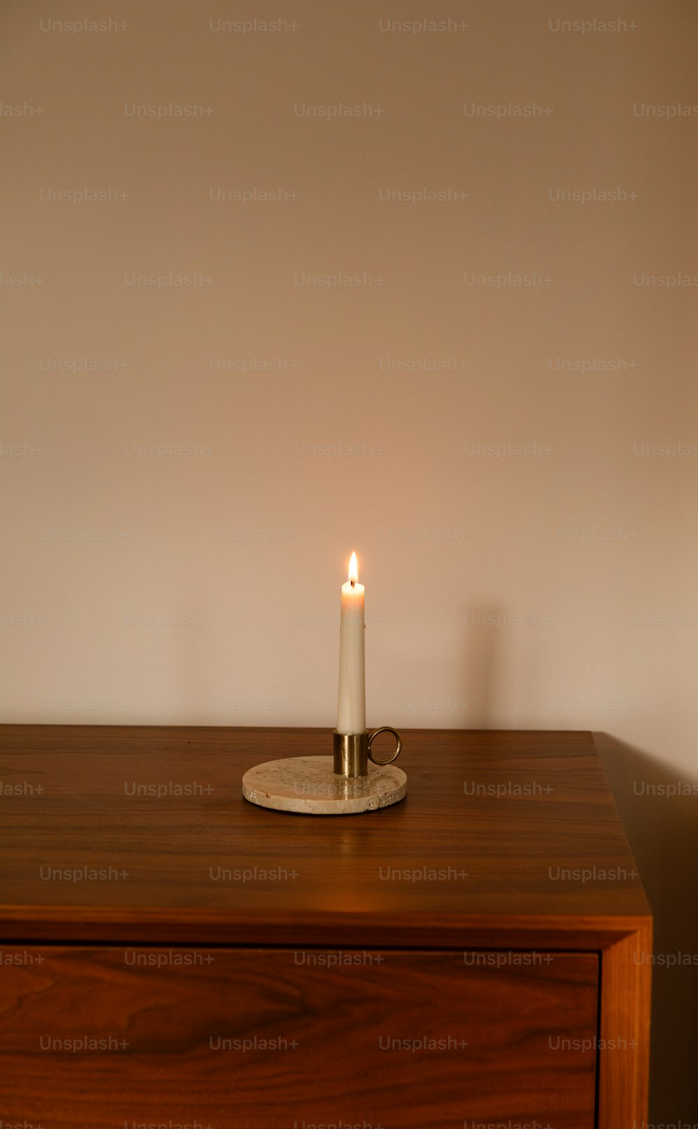 eine brennende Kerze, die auf einem Holztisch steht