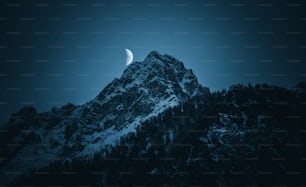 una montaña con una media luna en el cielo