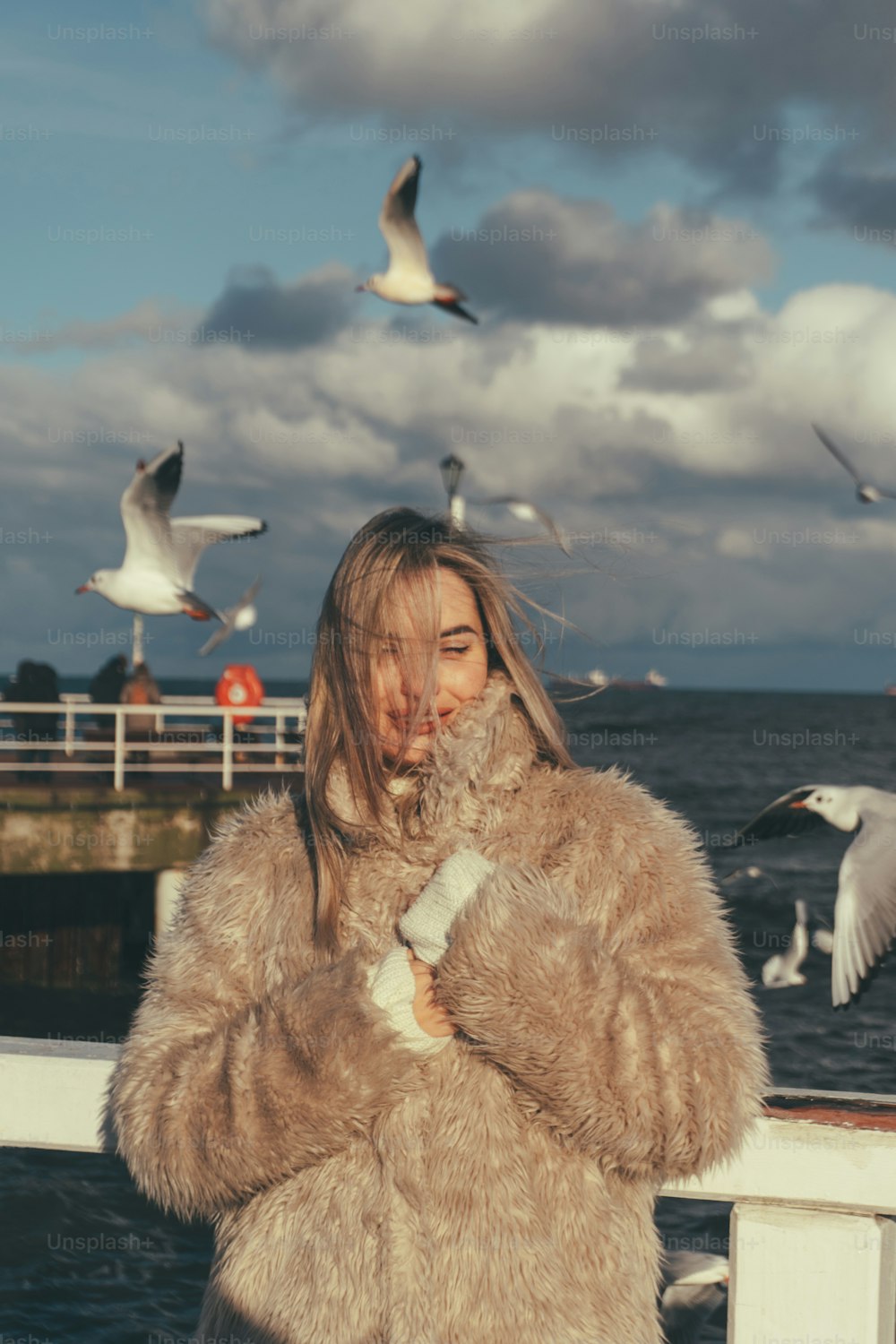 a woman standing on a pier with seagulls in the background