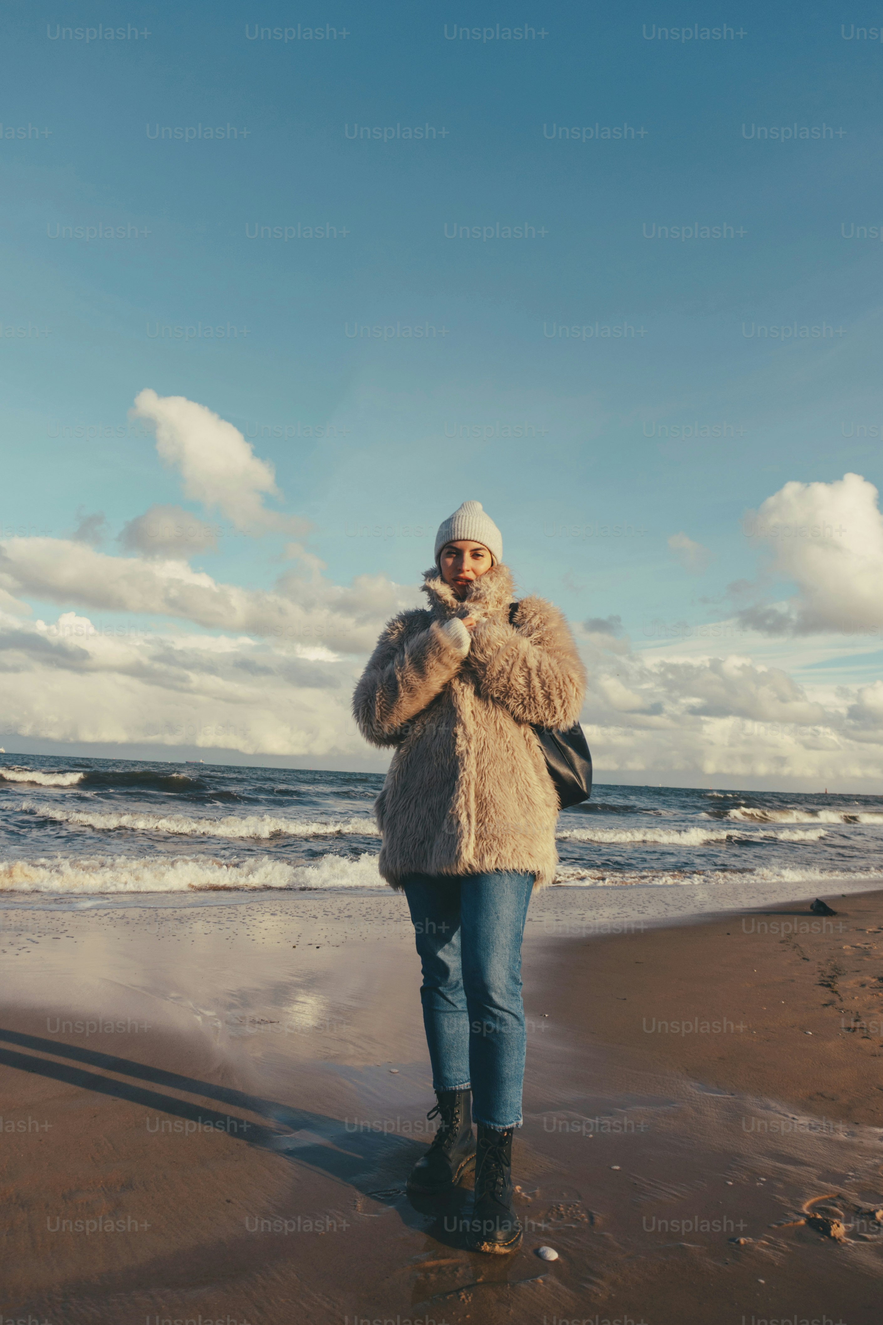 a woman standing on top of a beach next to the ocean