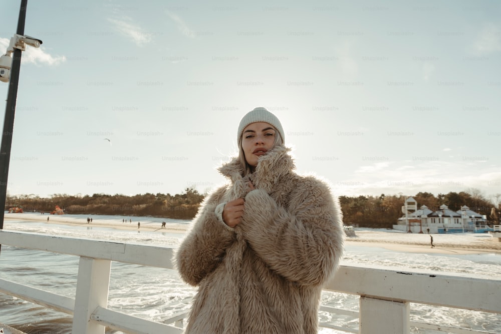 a woman in a fur coat standing on a pier