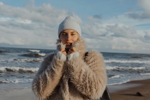 una donna in una pelliccia in piedi su una spiaggia
