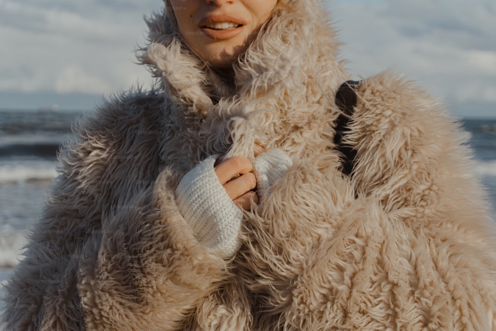 a woman in a fur coat on the beach